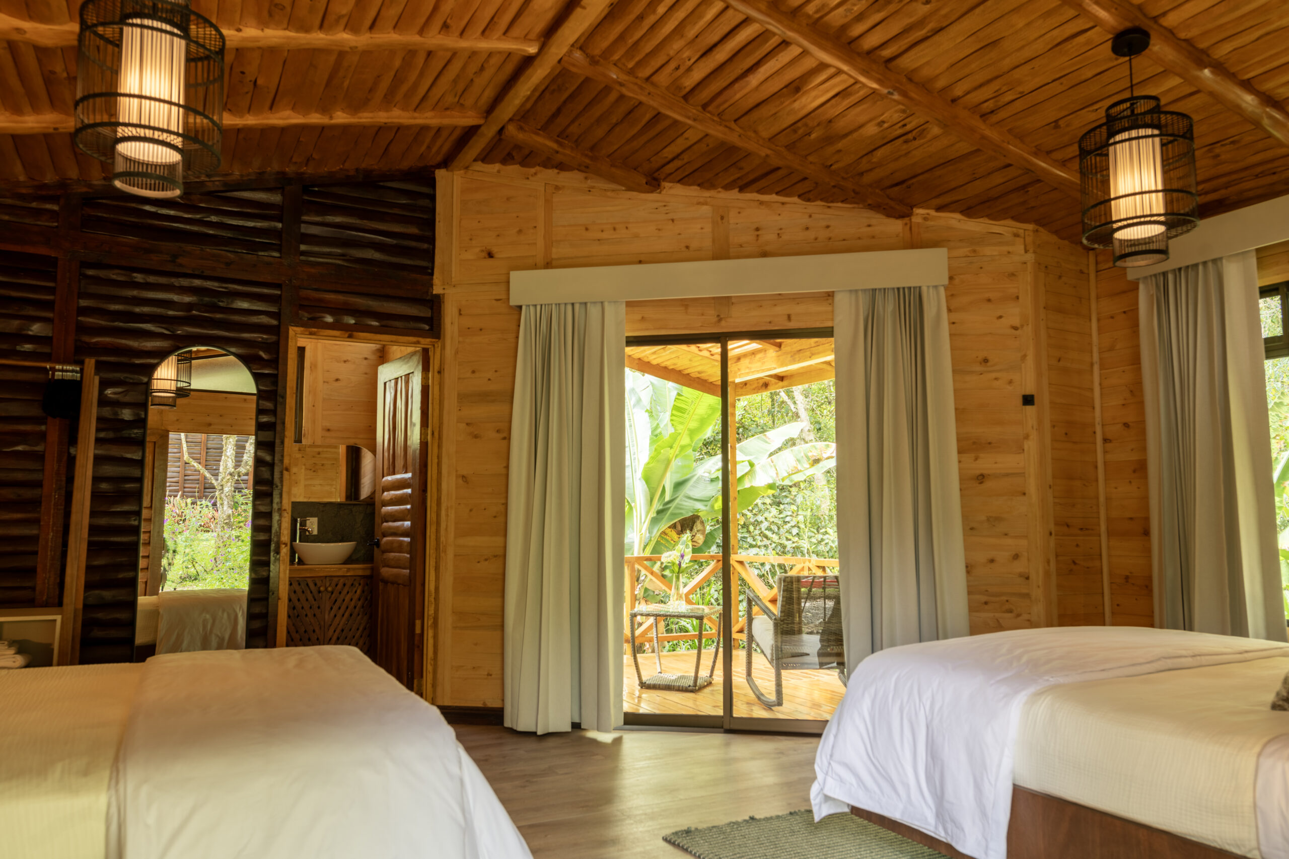 cozy cabin bedroom. through the open doorway you can see a porch and view of tropical greenery